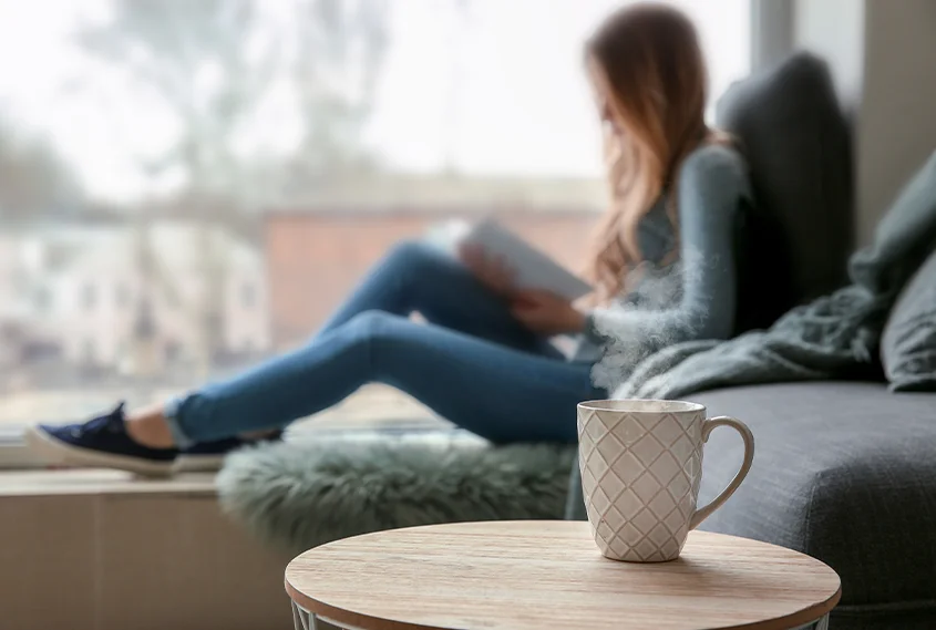 Woman reading a book by a cup of coffee