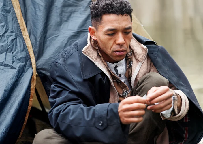 Man in warm clothes sitting by a tent